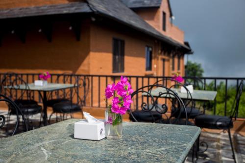 a vase of flowers sitting on a table on a balcony at Depche Village Resort in Bandīpur