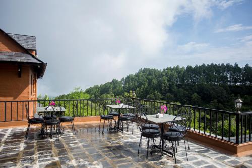 a patio with tables and chairs on a balcony at Depche Village Resort in Bandīpur