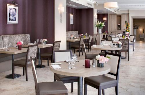 a restaurant with tables and chairs with flowers on them at The Originals Boutique, Hôtel Les Strélitzias in Juan-les-Pins
