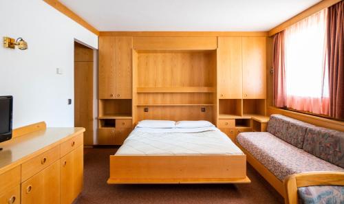 a hotel room with a bed and a desk at Apartments Lores in Selva di Val Gardena