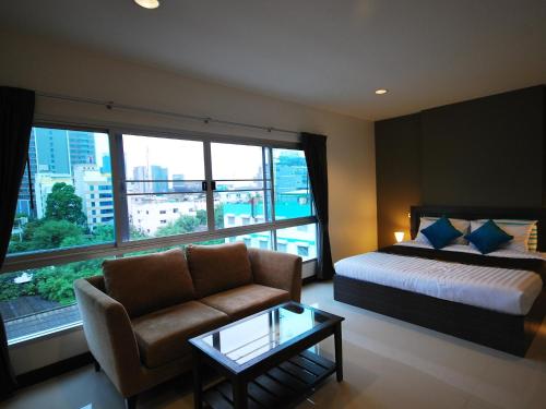 a hotel room with a bed and a couch and a window at Baan Mina in Bangkok