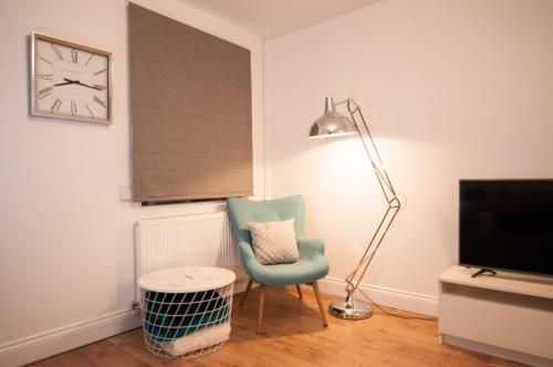 a room with a chair and a clock and a lamp at The Wellington - Stylish 3-Bedroom House, Sleeps 8, Ideal for Professionals in Burton upon Trent