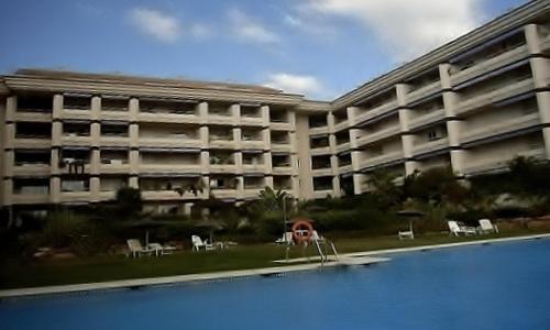 un gran edificio de apartamentos con piscina frente a él en Apartamento Milla de Oro en Marbella