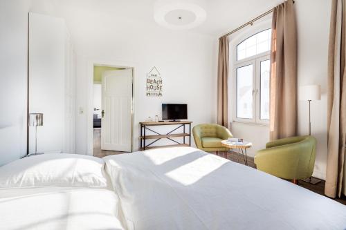 1 dormitorio blanco con 1 cama y 1 silla en Herr Friese, Wohnung Nr. 6, en Norderney