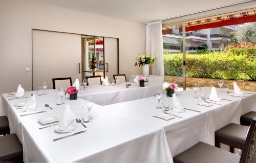 a set of tables with white tablecloths and flowers at The Originals Boutique, Hôtel Les Strélitzias in Juan-les-Pins