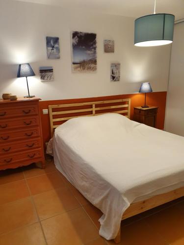 エーグ・モルトにあるMaison Les Pinsのベッドルーム1室(ベッド1台、ドレッサー、ランプ2つ付)
