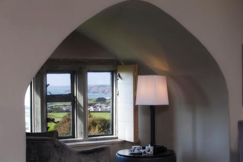 a room with two windows and a table with a lamp at Roch Castle in Roch