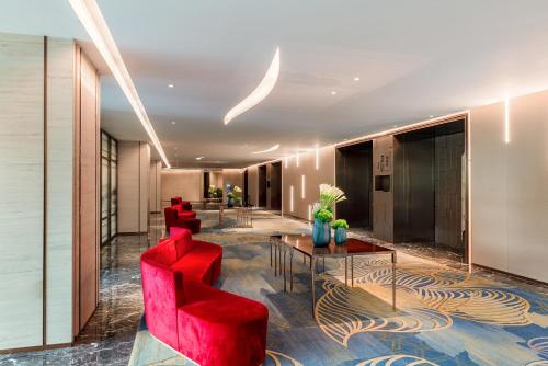 a lobby with red chairs and a table at Auto City Ruili Hotel in Jiading