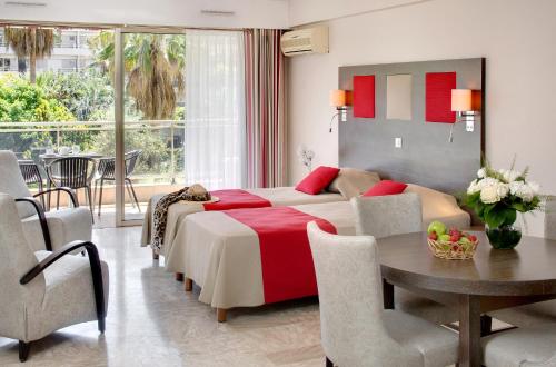 een slaapkamer met een bed en een tafel en een eetkamer bij The Originals Résidence, Les Strélitzias in Juan-les-Pins