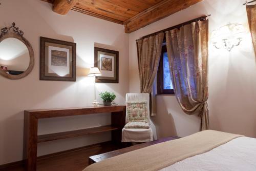 a bedroom with a bed and a chair and a mirror at Villa Russell Hotel&Apartments in Torla