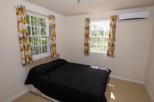 a bedroom with a bed and two windows at THE COTTAGE, SAINT DAVIDS in Christ Church
