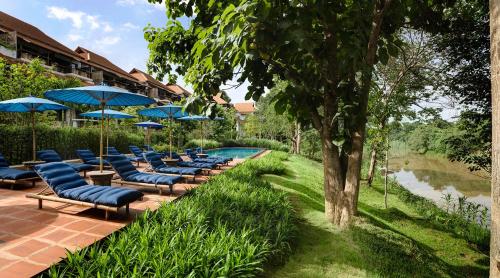 a row of chairs and umbrellas next to a pool at Raya Heritage - SHA Plus in Chiang Mai