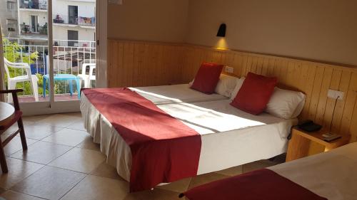 a bedroom with a large bed with red pillows at Hotel Piccadilly Sitges in Sitges