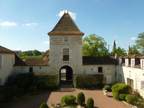 an old building with a gate in a yard at Logis Hotel Le Prince Noir in Sérignac-sur-Garonne