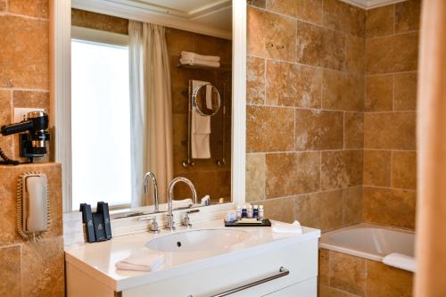 a bathroom with a sink, mirror and bath tub at Splendid Conference & Spa Resort in Budva