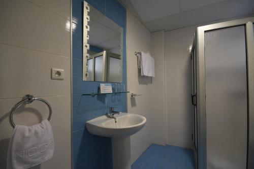 y baño con lavabo y ducha con espejo. en Apartamentos Tinoca, en Las Palmas de Gran Canaria