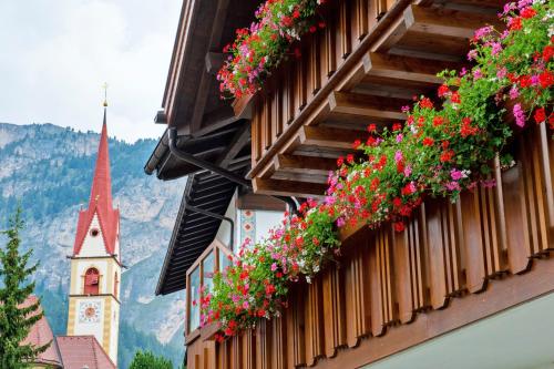 a building with flowers on the side of it with a church at Garni Crepaz in Selva di Val Gardena