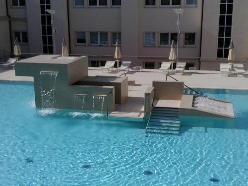a swimming pool with stairs and chairs in a building at Hotel Terme Marine Leopoldo II TERME & SPA in Marina di Grosseto