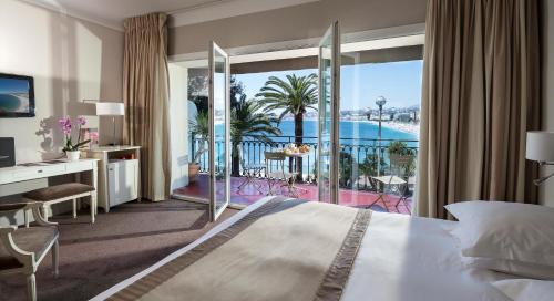 a bedroom with a bed and a balcony with a view at Hotel Suisse in Nice