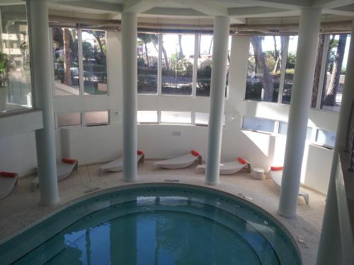 a swimming pool in a building with columns and windows at Hotel Terme Marine Leopoldo II TERME & SPA in Marina di Grosseto