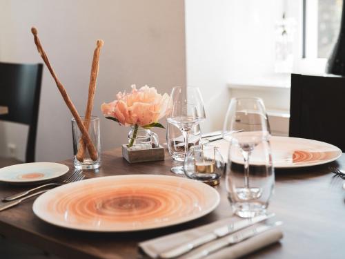 a wooden table with two plates and glasses on it at Hotel-Restaurant La Croix d’Or in Ballaigues