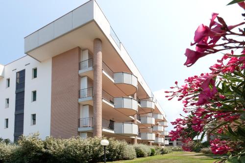 un palazzo alto con fiori rosa davanti di Le Residenze di Santa Costanza - Le Dimore a San Vincenzo