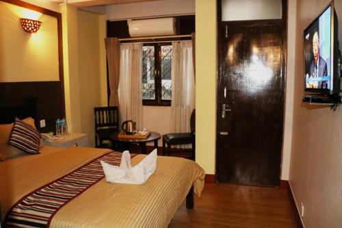 a hotel room with a bed and a door with a television at Hotel Yala Peak in Kathmandu