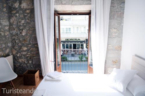 a bedroom with a white bed and a window at Apartamento Llerandi 1B - Céntrico y completamente reformado in San Vicente de la Barquera