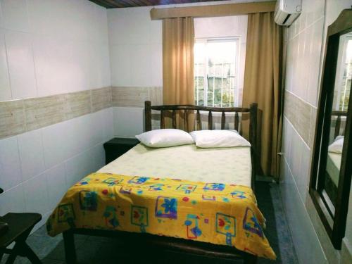 a small bedroom with a bed with a yellow blanket at Solar Dona Maria in Pinheira