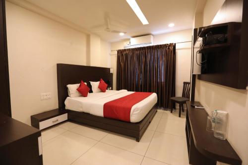 Una habitación de hotel con una cama con almohadas rojas. en Traders Hotel - Kankanady, Mangalore, en Mangalore