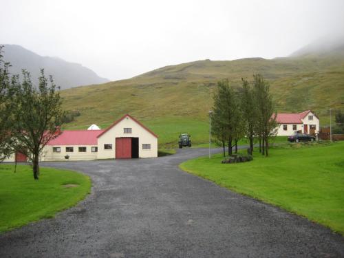 a road leading to a white building with a red door at Ásólfsskáli Cottage in Ásólfsskáli