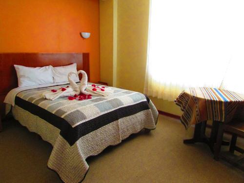a bedroom with a bed with two swans on it at Maya Inn in Puno