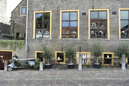 een bakstenen gebouw met tafels en stoelen ervoor bij B&B de Gusto in Schiedam