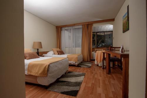 a hotel room with two beds and a desk at Hotel del Valle Azapa in Arica