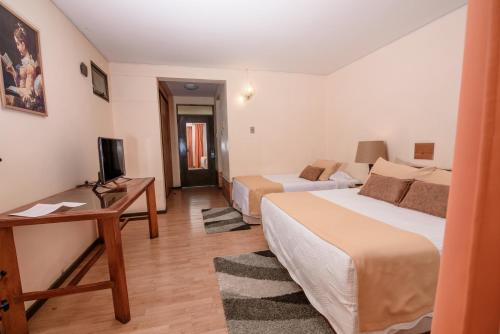 a hotel room with two beds and a desk at Hotel del Valle Azapa in Arica