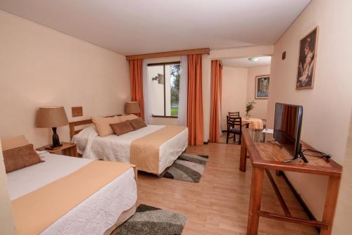 a hotel room with two beds and a television at Hotel del Valle Azapa in Arica