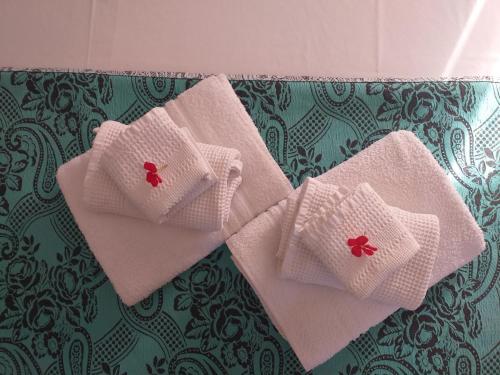 three white towels with red flowers on a bed at Le Terrazze Sul Pollino B&B in Civita