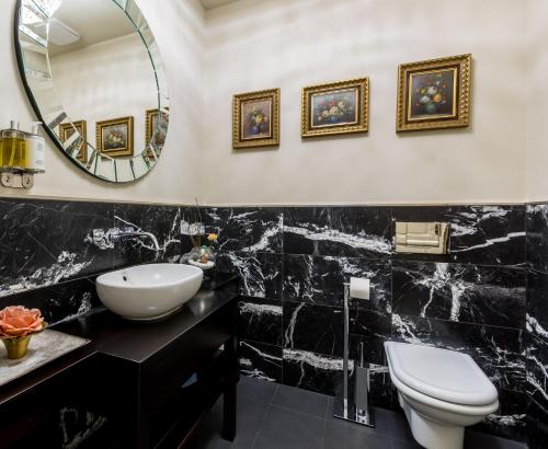 ein Badezimmer mit einem Waschbecken, einem WC und einem Spiegel in der Unterkunft Myo Hotel Caruso in Prag