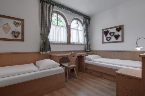 een kamer met 2 bedden en een stoel. bij Residence As'Odei in San Cassiano