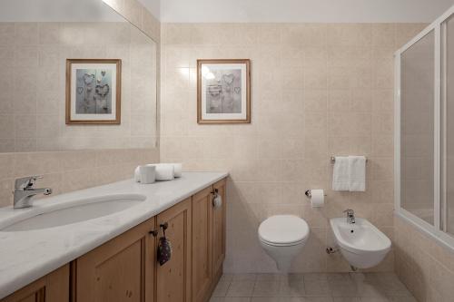 een badkamer met een wastafel, een toilet en een bad bij Residence As'Odei in San Cassiano