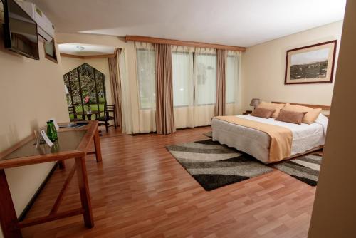 a bedroom with a bed and a table and a desk at Hotel del Valle Azapa in Arica