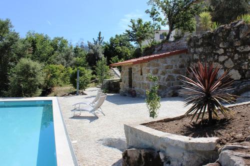 a swimming pool with a chair and a house at Villa Lugar do Pego in Tondela