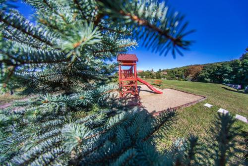a red play structure in a park next to a christmas tree at Borhotel Sziluett Farkasmály in Gyöngyös