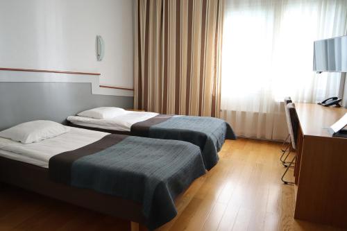 a hotel room with two beds and a television at Rokua Health & Spa in Rokua