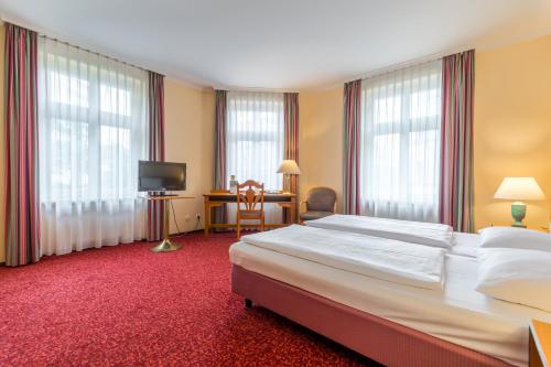 a hotel room with a large bed and a desk at Galerie Hotel Leipziger Hof in Leipzig