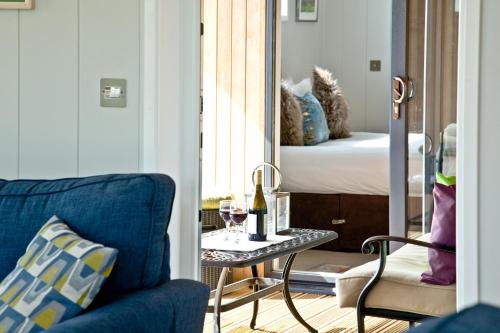 Habitación con sofá azul y mesa con una copa de vino. en Perry Lodge, Strawberryfield Park, en Cheddar