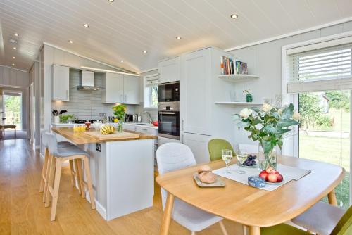 a kitchen and dining room with a table and chairs at Perry Lodge, Strawberryfield Park - Hot Tub - Free Parking & WiFi in Cheddar