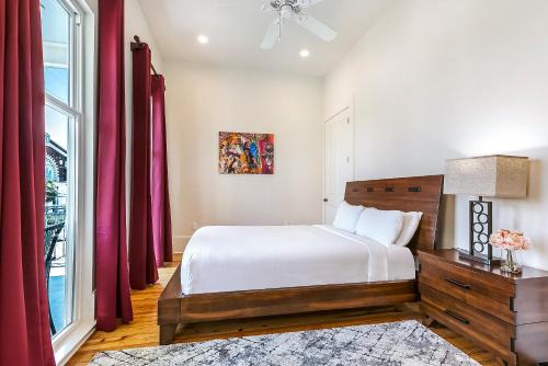 a bedroom with a bed and a window with red curtains at 3BR Cottage on Carondelet by Hosteeva in New Orleans