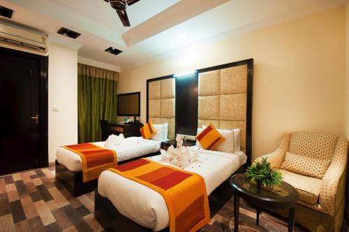 una habitación de hotel con 2 camas y una silla en The Oakland Plaza by Orion Hotels en Nueva Delhi