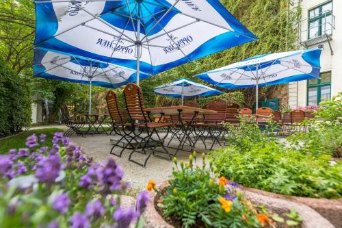 a table and chairs with umbrellas in a garden at Galerie Hotel Leipziger Hof in Leipzig